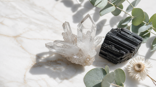 Clear quartz crystals and black tourmaline on white marble with fresh eucalyptus and natural daylight