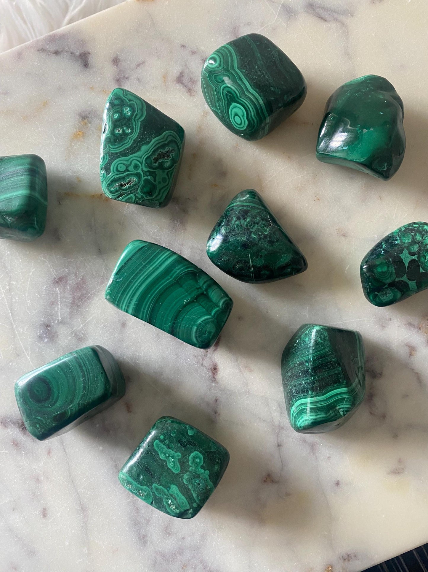 Malachite tumble stone close up showing green banding detail